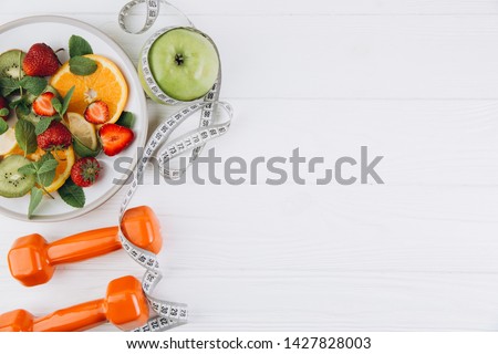Diet plan, menu or program, tape measure, water, dumbbells and diet food of fresh fruits on white background, weight loss and detox concept, top view