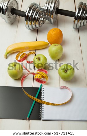 diet plan, menu or program, weight loss, measuring tape, dumbbells and dietary food fresh fruit on a white wooden table