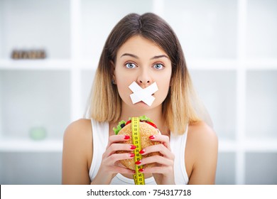 Diet. Portrait woman wants to eat a Burger but stuck skochem mouth, the concept of diet, junk food, willpower in nutrition