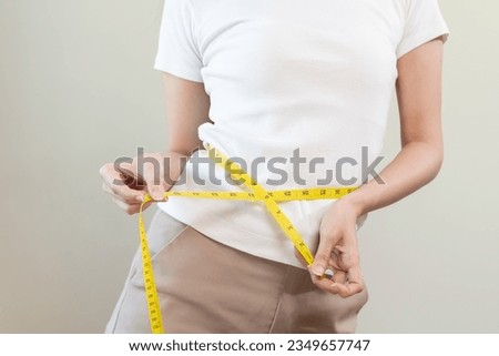 Diet, slim shape asian young woman standing, hand using measure tape around waist, body. Happy, pleasure girl slim slender on white background. Diet session for wellbeing health, eat good food people.