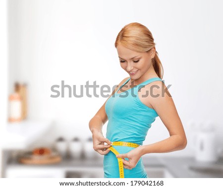 diet, sport and heath concept - beautiful sporty woman with measuring tape