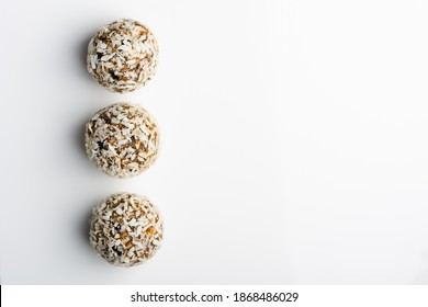 Diet vegetarian energy balls with nuts, dried fruit, chia, oats, cocoa, peanut butter and honey in coconut flakes. White background.