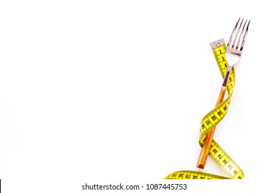 Diet, Weight Loss, Slimming Concept. Fork With Wound Measuring Tape On White Background Top View Space For Text