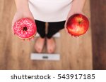 Diet. Woman Measuring Body Weight On Weighing Scale Holding Donut and apple. Sweets Are Unhealthy Junk Food. Dieting, Healthy Eating, Lifestyle. Weight Loss. Obesity. Top View