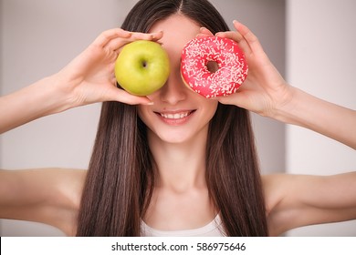 Diet. Woman Measuring Body Weight On Weighing Scale Holding Donut And Apple. Sweets Are Unhealthy Junk Food. Dieting, Healthy Eating, Lifestyle. Weight Loss. Obesity.