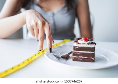 Diet Woman Posing Finger Walking Cross Measure Tape To Cake. Diet And Cheat Day Concept