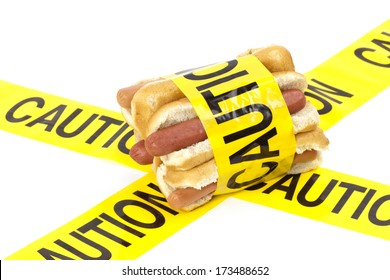 Dietary Fast Food Warning, Caution Of High Cholesterol And Saturated Fat, Unhealthy Nutrition Concept Image (Beef Sausages, Wieners And Hot Dogs With Buns Wrapped In Yellow Caution Tape)