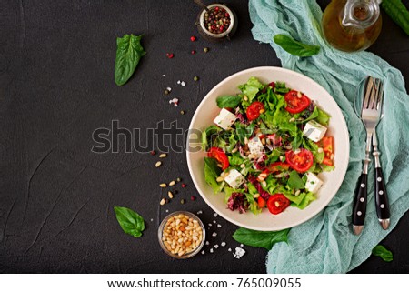 Dietary salad with tomatoes, feta, lettuce, spinach and pine nuts. Top view. Flat lay.