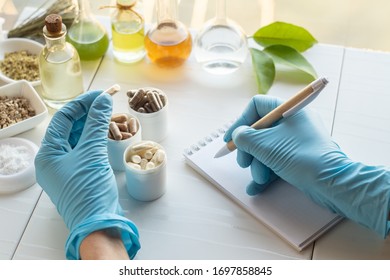 Dietary supplement capsules and ingredients. Hand of a pharmacist writes in a notebook