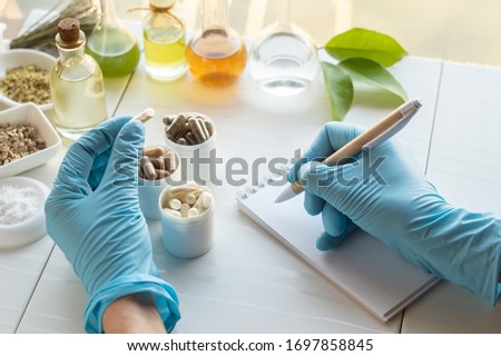 Dietary supplement capsules and ingredients. Hand of a pharmacist writes in a notebook

