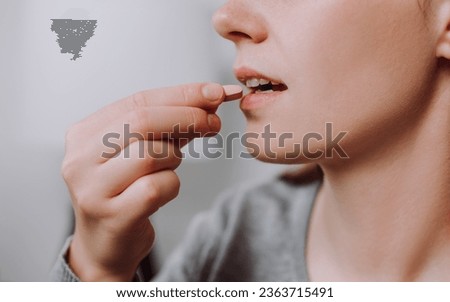 Dietary supplement concept. Close up of young caucasian woman holding little medical pill, take or eat vitamin C, D for treatment for skin, hair and nail strengthen, healthcare