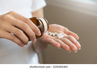 Dietary supplement or sick, asian young woman, girl hold pills, drugs medical tablet on hand pouring capsules from medication bottle, take vitamin for treatment for skin, hair at home, healthcare. - Powered by Shutterstock