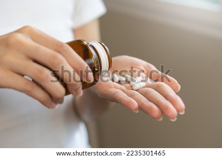 Dietary supplement or sick, asian young woman, girl hold pills, drugs medical tablet on hand pouring capsules from medication bottle, take vitamin for treatment for skin, hair at home, healthcare.