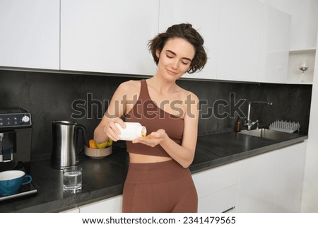 Dietary supplement, young fitness woman, girl hand holding medical pill, take or eat vitamin C, D for treatment for skin, hair and nail strengthen with glass of pure water at home, healthcare. Foto stock © 