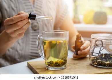 Nahrungsergänzungsmittel und Vitamine - Frau, die in einer Tasse Tee mit Pipette einen Tropfen Cbd-Öl zugibt. Anti-Stress