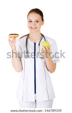 Dietician holding sweet doughnut and fresh healthy green apple. Isolated on white
