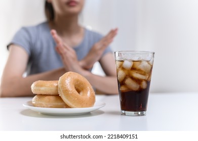 Dieting or good health concept. Young woman rejecting Junk food or unhealthy food such donut sweets or soda drink and choosing healthy food such as fresh fruit or vegetable. - Shutterstock ID 2218409151