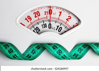Dieting Weightloss Slim Down Concept. Closeup Measuring Tape On White Weight Scale