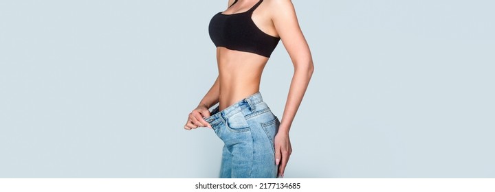 Dieting. Woman showing slim body after sport trainings, healthy eating. Weight loss concept. Thin woman in big pants, weight loss concepts. Slim girl wearing oversized pants. Woman shows weight loss.