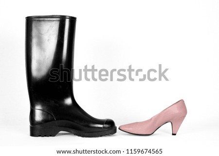 The difference between shiny black rubber boots and pink ladies pumps in front of a white house wall.