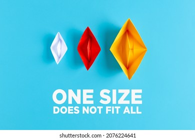 Difference, variety, plurality or diversity concept. Three paper boats with different size and colors on blue background with the text one size does not fit all.