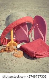 Different accessories using for relax on sand at beach. Straw hat, pink slippers, towel. Summer time and vacation time