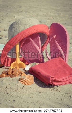 Different accessories using for relax on sand at beach. Straw hat, pink slippers, towel. Summer time and vacation time