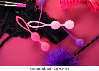 Different Adult Sex Toys On A Pink Background With Black Underwear