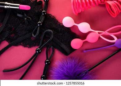 Different Adult Sex Toys On A Pink Background With Black Underwear