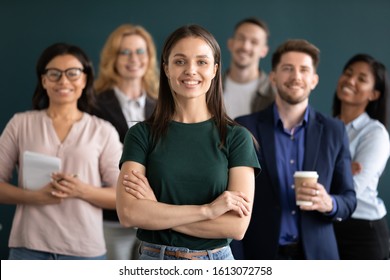 Different age and ethnicity businesspeople standing behind of female company chief business owner with hands crossed posture of confident independent businesswoman leader of multi-ethnic team concept