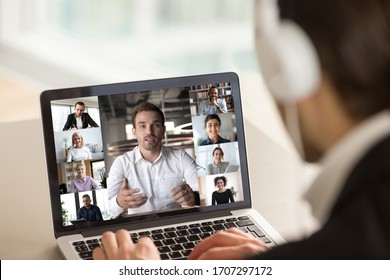 Different age and ethnicity diverse businesspeople participating at group videocall, laptop screen webcam view over man in headphones shoulder. Distant communication videoconference activity concept - Powered by Shutterstock