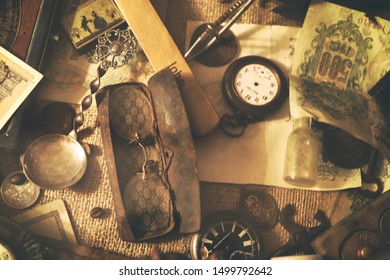 Different antique items on the table: old pocket watches, banknotes and coins of the Russian Empire, glasses in a case, silverware. Vintage background from a collection of antiques. Selected focus