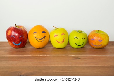 Different apples and orange with funny faces, tolerance, originality or friendship concept. 