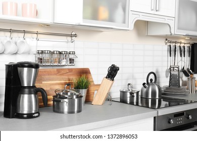 Different appliances, clean dishes and utensils on kitchen counter