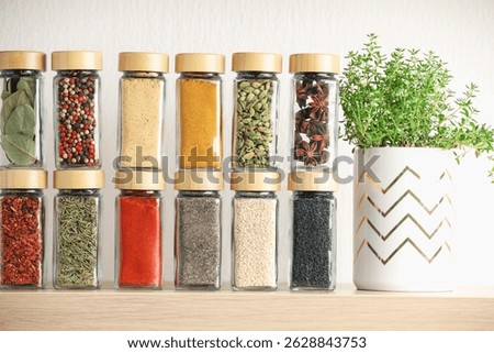 Different aromatic spices in jars on wooden shelf indoors