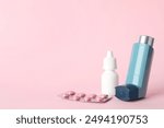 Different asthma medications on pink background, closeup. Space for text