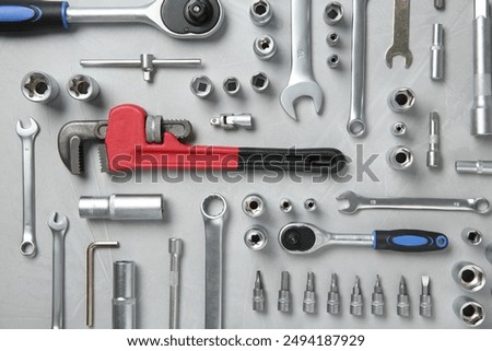 Different auto mechanic's tools on grey table, flat lay