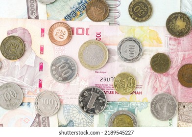 Different Banknotes And Coins Scattered On The Table View From Above