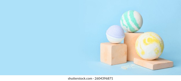 Different bath bombs on light blue background with space for text