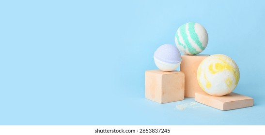 Different bath bombs on light blue background with space for text