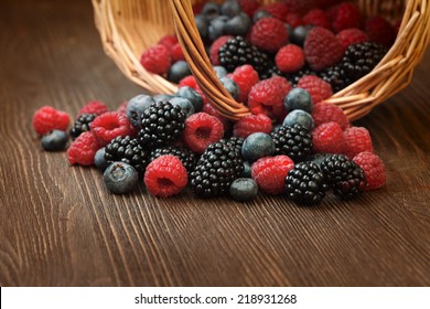 Different Berries (blueberries Raspberries Blackberries) In A Basket On A Wooden Table