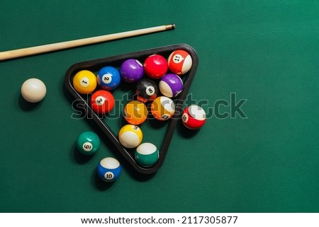 Different billiard balls with cue and rack on green table
