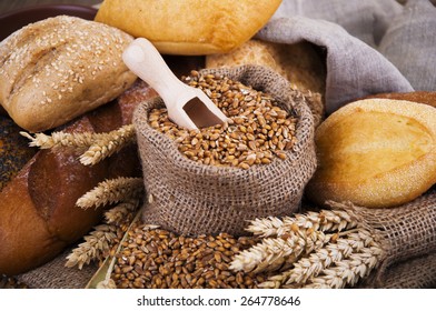Different bread with wheat in a small bag on a wooden background - Shutterstock ID 264778646
