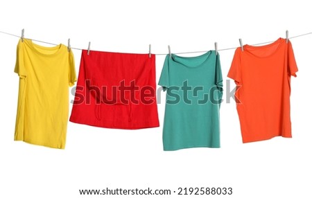 Different bright clothes drying on washing line against white background