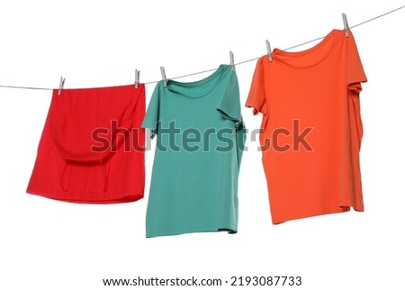 Different bright clothes drying on washing line against white background