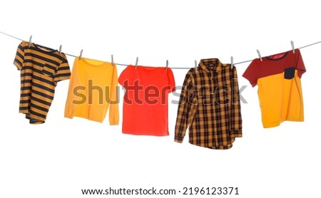 Different bright clothes drying on washing line against white background