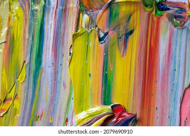 Different bright colors of oil paints are mixed on a palette close-up.