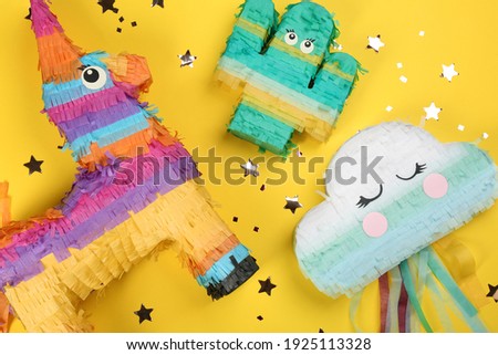 Different bright pinatas on yellow background, flat lay