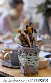 Different brushes in a designer ceramic rectangular glass on the table. Master class in pottery