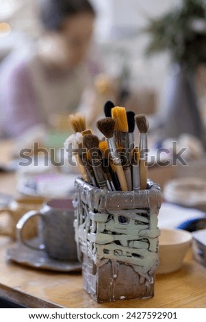 Different brushes in a designer ceramic rectangular glass on the table. Master class in pottery
